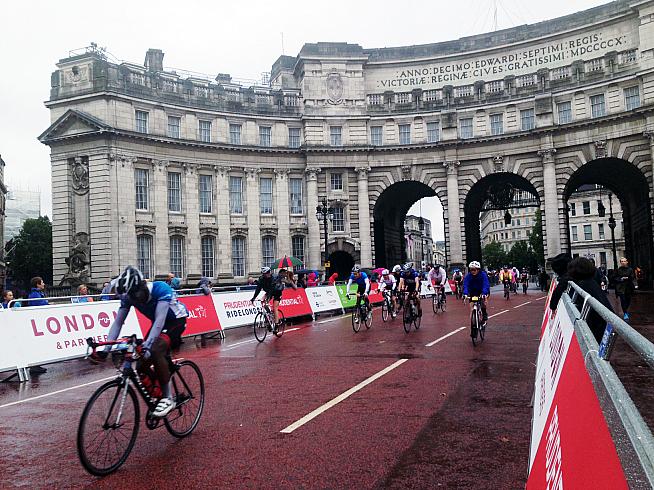 Riders on the rain-hit 2014 edition of the RideLondon 100 sportive enter the finish straight on The Mall.
