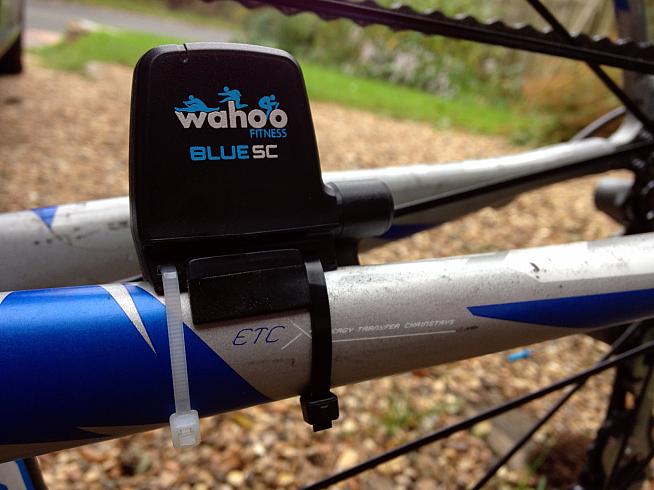 The Wahoo Blue SC cadence sensor pairs with the RFLKT+ head unit to show your cadence data. It actually comes with a neat rubber strap to fit to your chainstay  so you can avoid the zipties.