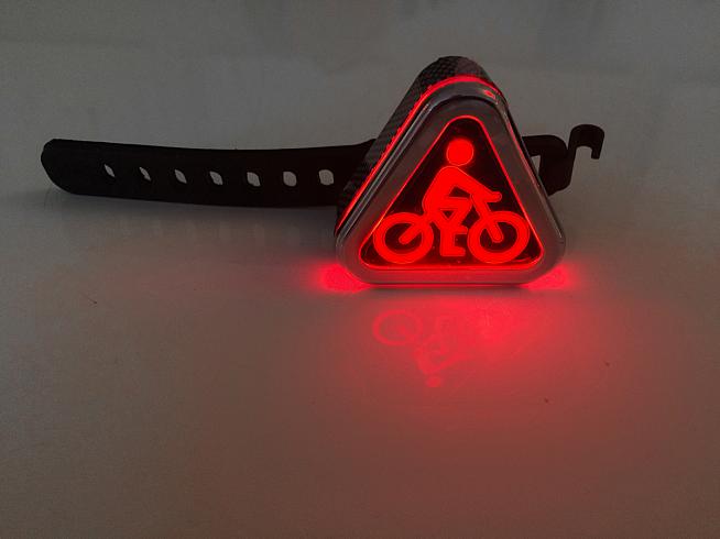 The rear Triangular Symbol light attaches easily to your bike or helmet with a secure rubber strap.